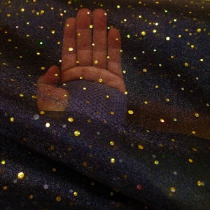 May include: Black sheer fabric with gold glitter dots. The fabric is draped over a hand.