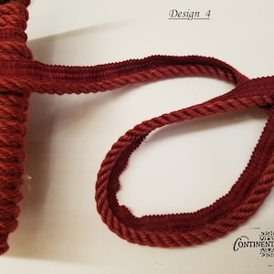 May include: Burgundy red braided cord trim with a flat backing. The trim is shown in a loop and on a spool. The text "Design 4" and "Continental Fabric" are visible in the image.