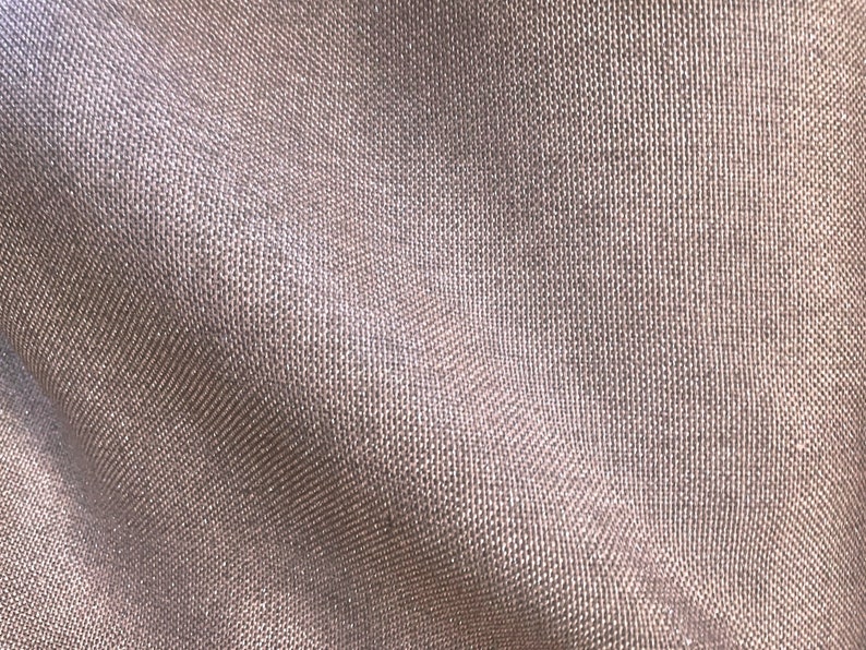 Pode incluir: Close-up de um tecido texturizado, tecido em uma cor marrom claro. O tecido tem um brilho sutil e uma apar&ecirc;ncia ligeiramente enrugada.