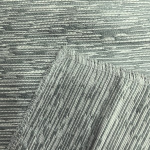 May include: Close-up of a grey and white textured fabric with a subtle woven pattern. The fabric has a slightly iridescent sheen.