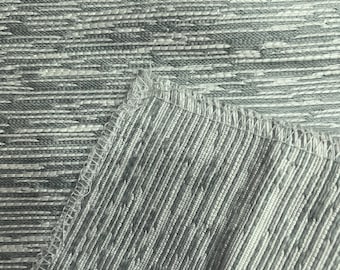 May include: Close-up of a grey and white textured fabric with a subtle woven pattern. The fabric has a slightly iridescent sheen.