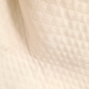 May include: Close-up of a white fabric with a subtle diamond pattern. The fabric has a soft, smooth texture.