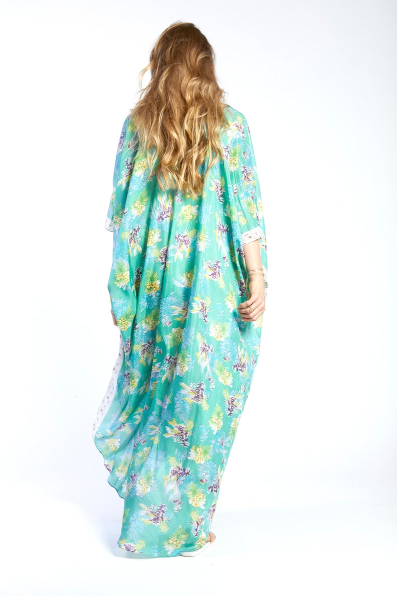 May include: A long, flowing turquoise kaftan with a floral print. The kaftan has a loose, comfortable fit and is perfect for warm weather.