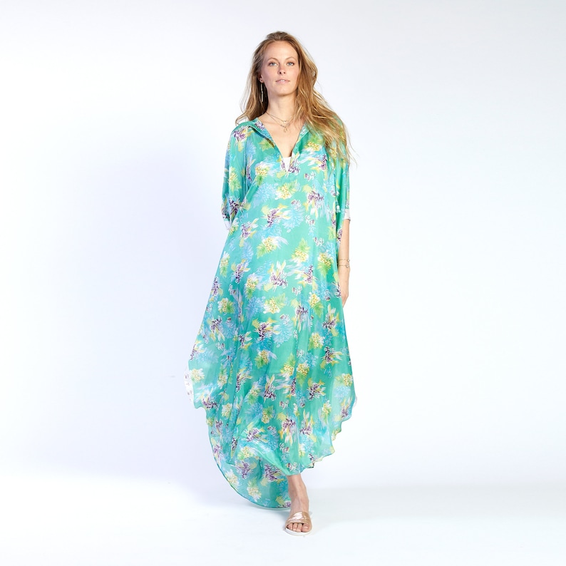 May include: A long, flowing, turquoise dress with a floral print. The dress has a V-neckline and a long, flowing skirt.