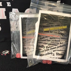 May include: Two clear plastic bags containing small red dice and a card with the text "RANDOM THOUGHTS BY DEVIN KNIGHT" and a list of random thoughts. The card is white with black text.