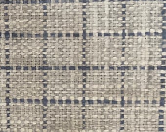 May include: A close-up of a woven fabric with a checkered pattern in shades of beige and blue.