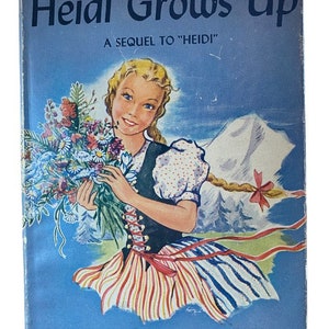 Pode incluir: Uma capa de livro com fundo azul e uma menina segurando um buquê de flores. O título do livro é "Heidi Grows Up" e o subtítulo é "A Sequel to "Heidi". O autor é Charles Tritton, tradutor de Johanna Spyri.