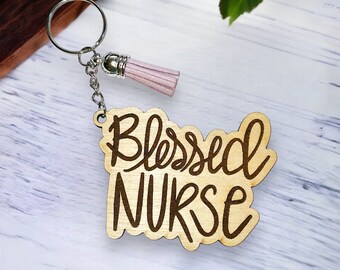 May include: Wooden keychain with a pink tassel and the words "Blessed Nurse" engraved on it.