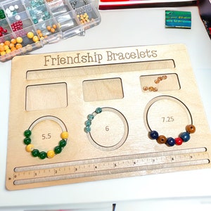 May include: Wooden board with three circles for making friendship bracelets. The circles are labeled 5.5 inches, 6 inches, and 7.25 inches. There is a ruler on the bottom of the board.