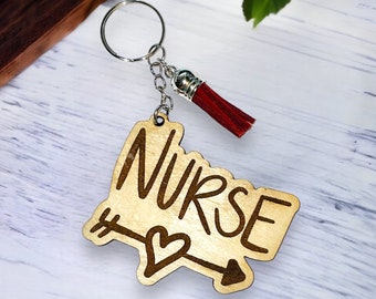 May include: Wooden keychain with a red tassel. The keychain features the word "NURSE" with an arrow and heart design.