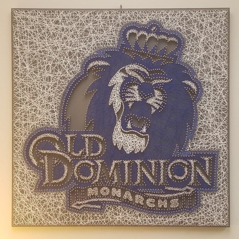 Peut inclure: Une &oelig;uvre d'art en fil repr&eacute;sentant le logo de l'universit&eacute; Old Dominion. Le logo pr&eacute;sente un lion bleu avec une couronne, les mots "Old Dominion" et "Monarchs" en fil blanc.