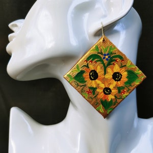 May include: Gold square earrings with a hand-painted design of sunflowers and green leaves.
