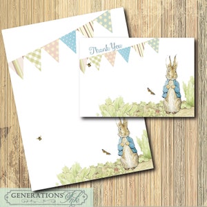 May include: A thank you card featuring Peter Rabbit from Beatrix Potter's children's book. The card has a blue and white bunting with the words "Thank You" printed on it. The card is surrounded by a green leafy background.