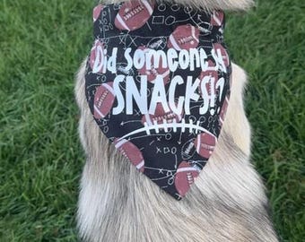 Könnte beinhalten: Ein grau-weißer Hund, der ein schwarzes Bandana mit weißem Text trägt, auf dem "Did someone say SNACKS!" steht, und ein Fußballmuster.