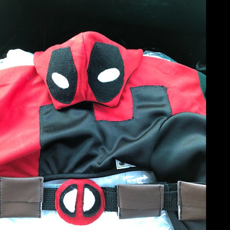 May include: Red and black hooded costume with a white eye mask and a brown belt with a red and white eye mask on the front.