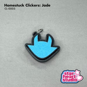 Puede incluir: Un llavero Homestuck Clickers: Jade con un contorno negro y un interior azul claro. El llavero tiene una forma única e incluye un llavero plateado. El texto "Homestuck Clickers: Jade" y "CL-0005" son visibles.