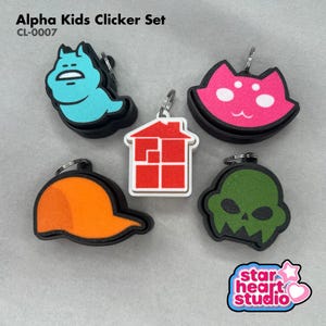 May include: Alpha Kids Clicker Set CL-0007 featuring five colorful plastic clickers with metal keyrings. The set includes a blue creature, a pink cat face, a white house with red squares, an orange cap shape, and a green skull-like figure.
