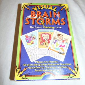 May include: A boxed game titled "VISUAL BRAIN STORMS" with the tagline "The Smart Thinking Game." The box is blue with yellow lightning bolts and orange text. Three game cards are visible, featuring colorful illustrations and text. The box reads "100 of the World's Best Brainteaser Questions."