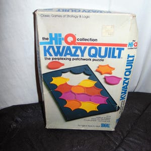 May include: A vintage "Kwazy Quilt" puzzle box from the Hi-Q collection. The box features the text "Kwazy Quilt" and "The perplexing patchwork puzzle". The puzzle includes a dark blue frame and colorful, oddly shaped pieces.