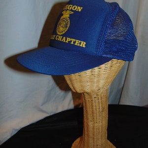 May include: Blue and yellow mesh trucker hat with the text "Oregon 4-H Chapter" on the front.
