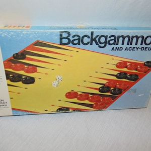 May include: A blue and yellow box for a Backgammon board game with the text "Backgammon and Acey-Deucy" on the front. The box shows a game board with red and black playing pieces and two white dice.