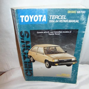 May include: A vintage Toyota Tercel 1984-94 repair manual. The cover is blue with the Toyota logo and Tercel model name in white. The manual includes wiring and vacuum diagrams. The image shows a beige Tercel car.