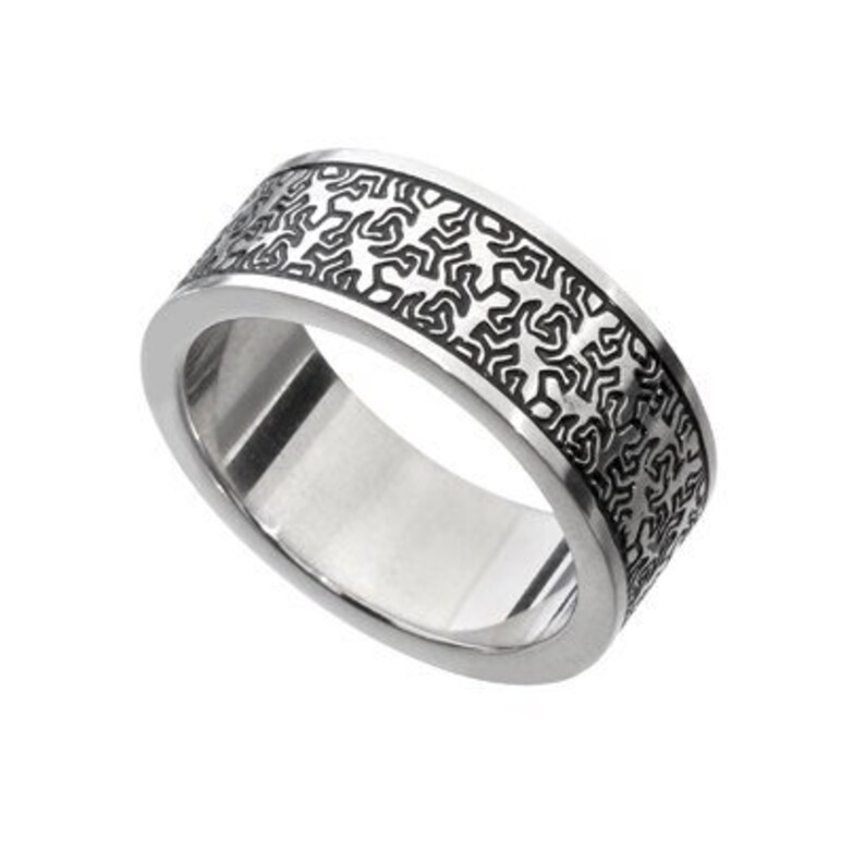 May include: A silver ring with a black patterned design. The pattern is intricate and covers the entire band of the ring.
