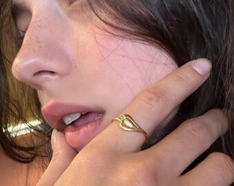 May include: A gold-toned ring featuring a delicate, open-work heart design on the band. The ring includes a small, singular clear stone set at the top point of the heart shape, creating a subtle focal point on the thin, polished metal band.