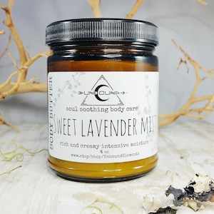May include: A glass jar of Sweet Lavender Mist body butter, labelled "Unbound" and "soul soothing body care". The jar is 4 oz and is on a white surface.
