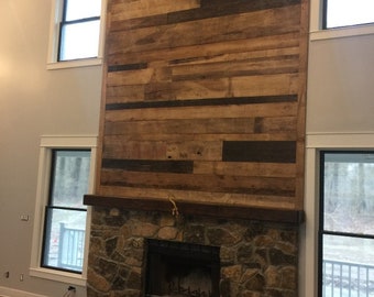 May include: A stone fireplace with a wood mantel and a wood-burning fireplace insert. The fireplace is surrounded by a rustic wood wall.