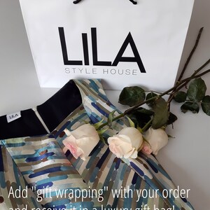 May include: A white gift bag with black handles and the text "LILA STYLE HOUSE" printed on the front. The bag is sitting on top of a patterned fabric with white roses.