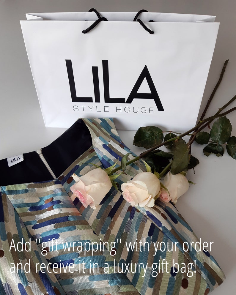 May include: A white gift bag with black handles and the text "LILA STYLE HOUSE" printed on the front. The bag is sitting on top of a patterned fabric with white roses.