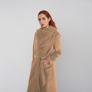 Peut inclure: Un long manteau marron à col large et à ceinture. Le manteau est fait d'un tissu doux et duveteux.