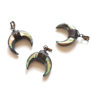 May include: Three silver crescent moon pendants with iridescent abalone shell inlays. Each pendant is wrapped with silver wire and has a silver loop for attaching a chain.