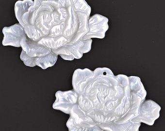 May include: Two white, pearl-like, flower-shaped pendants with a hole at the top for stringing. The flowers have a raised, textured design.