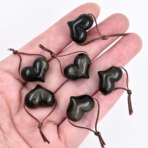 Puede incluir: Seis colgantes de piedra de sol negra en forma de coraz&oacute;n con cordones marrones. Los colgantes miden aproximadamente 2,5 cm.