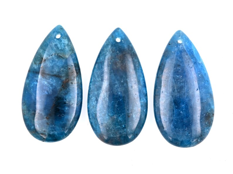 May include: Three teardrop-shaped blue gemstone pendants with a hole at the top for stringing.