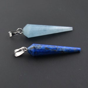 Può includere: Due ciondoli in pietra preziosa con un anello in argento. Il ciondolo a sinistra è in acquamarina blu chiaro. Il ciondolo a destra è in lapislazzuli blu scuro.