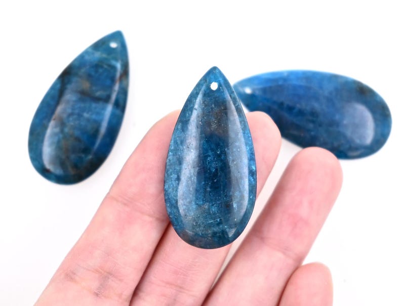 May include: Three teardrop-shaped blue gemstone pendants with a hole drilled at the top for stringing.