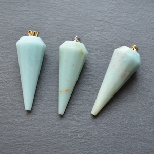 Può includere: Tre ciondoli in cristallo blu chiaro sfaccettati con anelli a salto in oro e argento. I ciondoli hanno la forma di un cono con una punta appuntita.