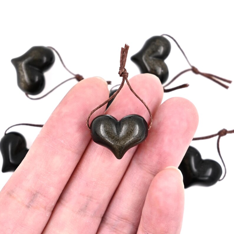 Puede incluir: Un conjunto de ocho colgantes en forma de coraz&oacute;n de pirita dorada con cordones marrones. Los corazones est&aacute;n pulidos y tienen un brillo met&aacute;lico.