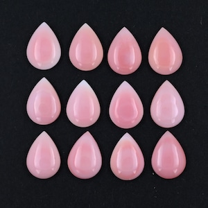 May include: Twelve smooth, polished, teardrop-shaped pink gemstones arranged in a grid of three rows and four columns. Each stone features a rounded base and a pointed top, displaying a consistent light pink hue with a glossy, reflective surface.