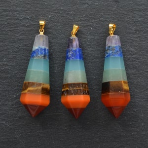 Peut inclure: Trois pendentifs dorés avec sept pierres précieuses superposées en forme pointue. Les pierres précieuses sont l'améthyste, le lapis-lazuli, l'aigue-marine, l'aventurine, l'œil de tigre, la cornaline et le jaspe rouge.