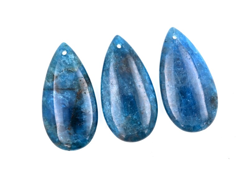 May include: Three teardrop-shaped blue gemstone pendants with a hole at the top for stringing.