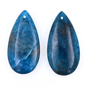 May include: Two teardrop-shaped blue gemstone pendants with a hole at the top for stringing.