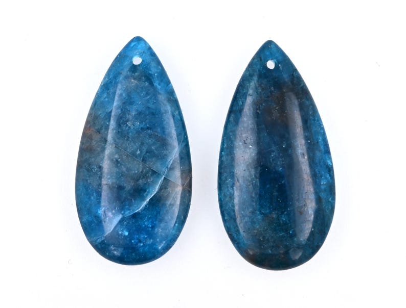 May include: Two teardrop-shaped blue gemstone pendants with a hole at the top for stringing.