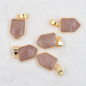 Puede incluir: Cinco colgantes chapados en oro con inserciones de piedras preciosas rosadas y blancas. Los colgantes tienen forma de punta de flecha y presentan un diseño geométrico.