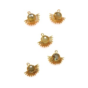 以下が含まれることがあります： 虹色の緑色の宝石の中心を持つ、金色のサンバーストチャームが5つあります。