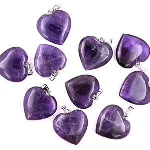 May include: Ten amethyst heart-shaped pendants with silver bail loops. The pendants are all approximately the same size and shape, and they are all a deep purple color.