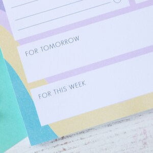 Op de afbeelding: Een witte plannerpagina met een lichtpaarse en gele achtergrond. De pagina heeft twee secties met de labels "Voor morgen" en "Voor deze week".